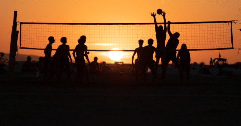 Photo d'un groupe jouant au Volley ball sur la plage au coucher de soleil
